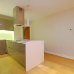 Modern kitchen with island and wooden floor.