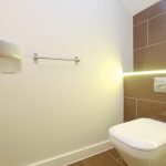 Modern bathroom with wall-mounted toilet and towel rail.