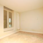 Empty cream room with radiator and blinds.