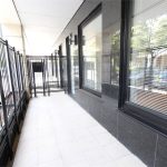 Outdoor tiled area with black railings and windows