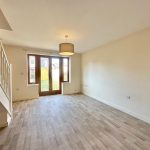 Bright empty living room with wooden flooring.