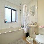 Modern white bathroom with bathtub and window.