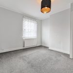 Empty carpeted room with pendant light and window.