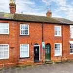 Row of brick terraced houses with For Sale sign.