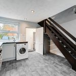 Modern kitchen with laundry and wooden staircase.