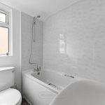 White modern bathroom with tub and window.