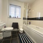 Modern bathroom with bathtub and striped mat.