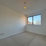 Empty carpeted room with window and light bulb.