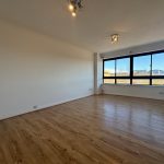 Bright empty room with wooden flooring and windows