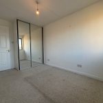 Empty bedroom with carpet and mirrored wardrobe.