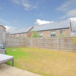 Fenced backyard with patio furniture and cloudy sky.