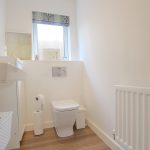 Modern bathroom with white fixtures and window.