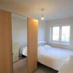 Minimalist bedroom with wardrobe and large window