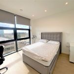 Modern bedroom with large window and city view.