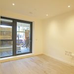 Empty room with wooden floor and large windows.