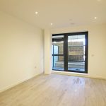 Spacious modern room with wooden flooring and window.