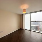 Empty room with large window and wooden floor.