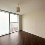 Empty room with large window and wooden floor.