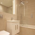 Modern beige tiled bathroom with shower and sink.