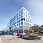 Modern office building with parked cars outside.