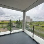 Cityscape view from modern balcony with glass railing.