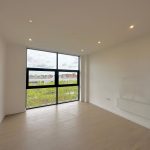 Empty room with large windows and wooden floor.