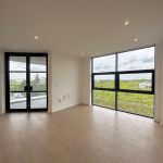 Bright empty room with large windows and wooden floor.