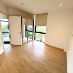 Empty bright room with wooden floor and large windows.