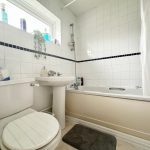 Modern bathroom with bathtub and white tiles.