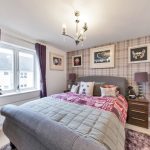 Cosy bedroom with patterned bedding and framed pictures.