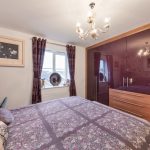 Cosy bedroom with floral bedding and chandelier.