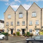 Terraced houses with parked cars on street.