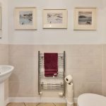 Toilet with paintings and towel rack.