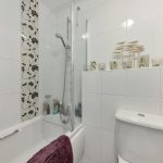 White bathroom with floral tiles and purple towel