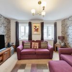 Cosy living room with purple sofas and wallpaper