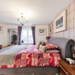 Modern bedroom with decorative art and plush furnishings.