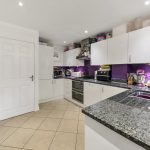 Modern kitchen with purple accents and appliances.