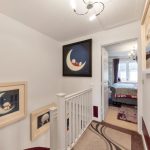 Hallway with framed artwork and carpeted stairs.