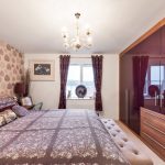 Cosy bedroom with patterned wallpaper and plush furnishings.