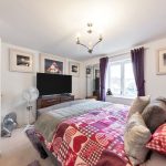 Cosy bedroom with TV, patterned bedspread, purple curtains.