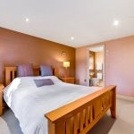 Modern bedroom with ensuite bathroom and wooden furniture.