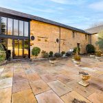 Stone courtyard outside large rustic building with windows.