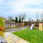 Back garden with play area and potted plants.