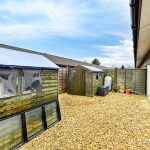 Backyard with sheds on gravel surface.