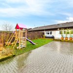 Sunny garden with playground and patio area.