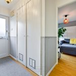 Modern hallway leading to living room with grey sofa.