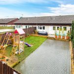 Back garden with children's play equipment and patio.