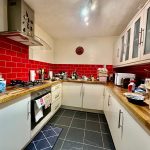 Modern kitchen with red tiles and wooden counters.