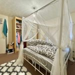 Bedroom with canopy bed and open wardrobe.