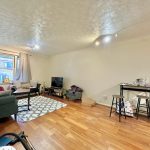 Spacious living room with wooden flooring and furniture.